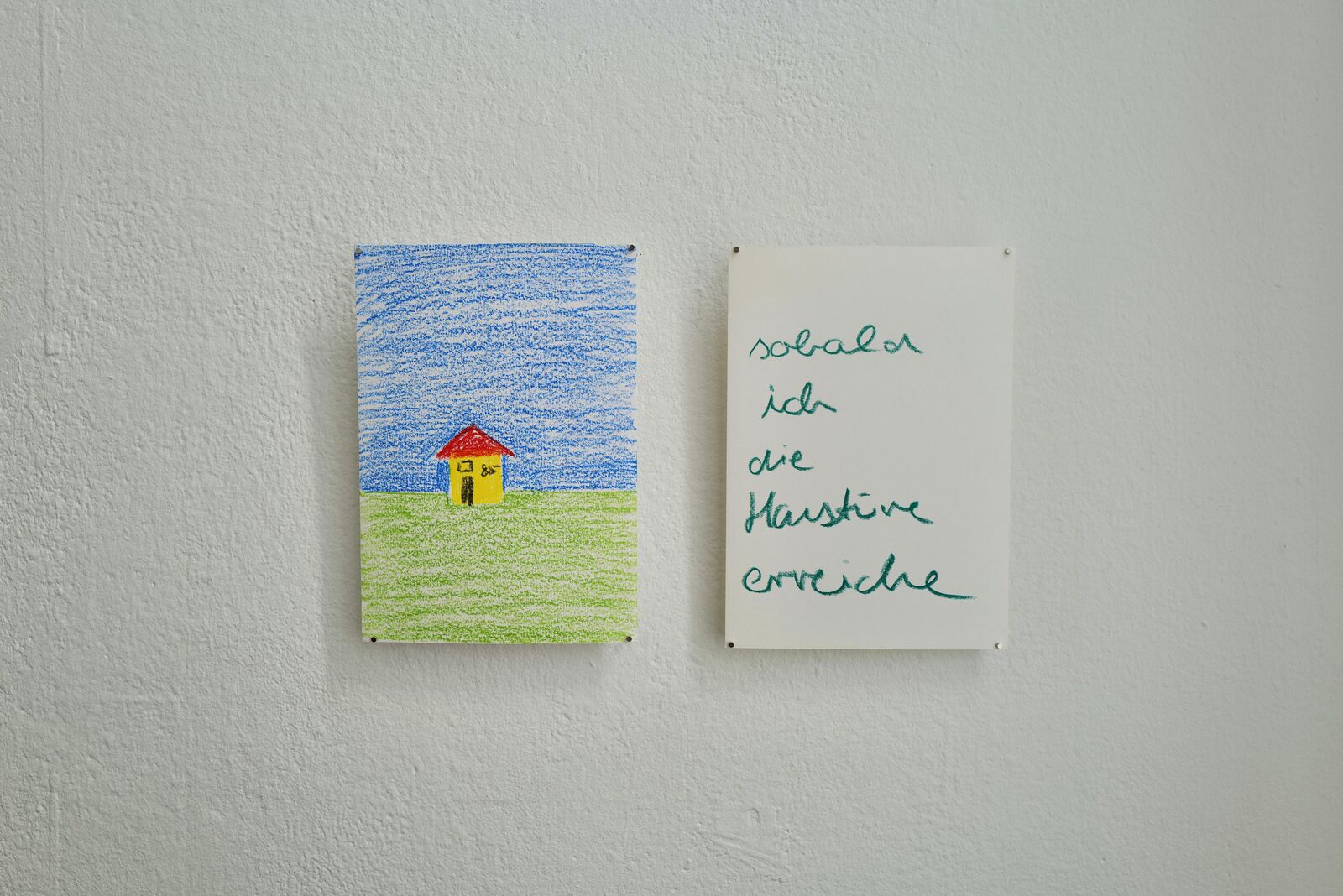 A coloured-pencil drawing of a small house under a blue sky next to a handwritten page reading ‘sobald ich die Haustüre erreiche’