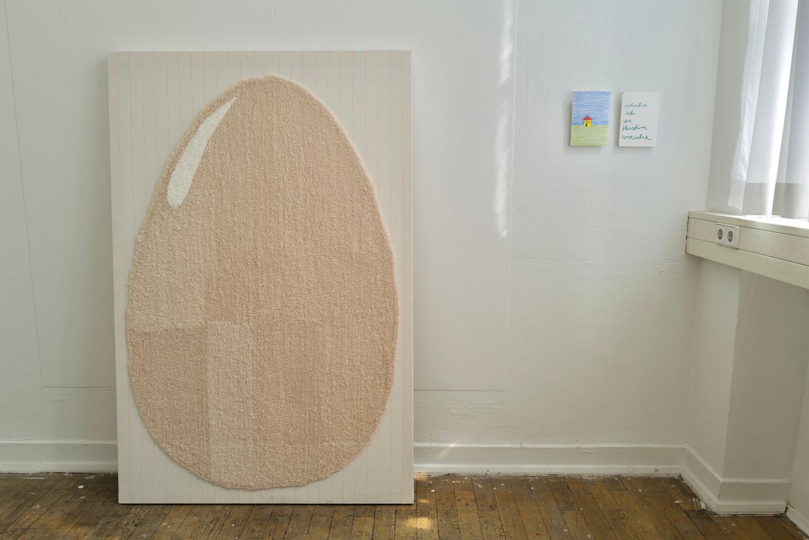 L’Uovo: an egg as tall as a person, made of pale wool on monk’s cloth, leaning against a white wall